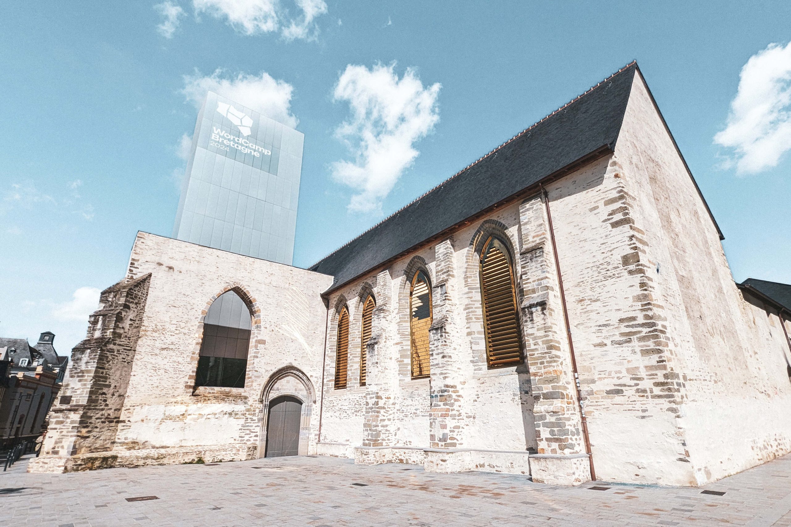 Photo en couleur de l'extérieur du couvent des Jacobins depuis la place Sainte-Anne, avec son toit d'ardoise, son ancienne église et la tour signal.